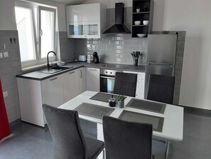 A modern kitchen with a central island, built-in appliances, and a window providing natural light. - Apartments Dobrila - One Bedroom Apartment With Terrace and sea View - B1 (Jelsa)