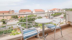 A balcony with a round table and two striped lounge chairs, overlooking a residential area with red-roofed houses. - Apartments Antonio - Comfort One-bedroom Apartment With Balcony and Sea View - 4 (Tucepi)