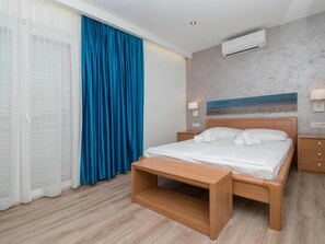 Ein Hotelzimmer mit Bett, Nachttisch, einer Sitzbank, einer Klimaanlage und einem Bild an der Wand.