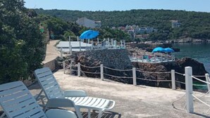 A coastal area with a stone wall, seating, and a view of the sea and hills. - Apartments Lux Lukić Utjeha - Triple Room (Utjeha)