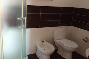 Ein Badezimmer mit einer Bio-Toilette, einer Toilette und einer Glasabtrennung.