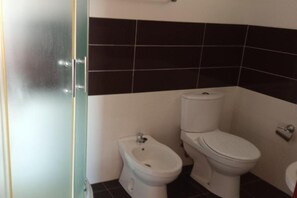 Ein Badezimmer mit integriertem Bidet, Toilette und einer Duschkabine aus Glas.