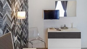 Moderni kylpyhuone, jossa on kuvioitu seinä, peili, litteänäyttöinen televisio ja pelkistetty pesuallas.