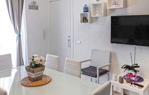 A modern living room with a flat-screen TV, white furniture, and decorative items on shelves. - Lovely apartment in Donnalucata with WiFi (Donnalucata)