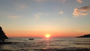Um pôr do sol sobre o oceano com um barco ao longe.