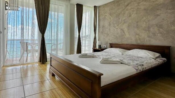 Habitació d'hotel amb llit de fusta, un balcó amb cadira i vista a l'exterior.