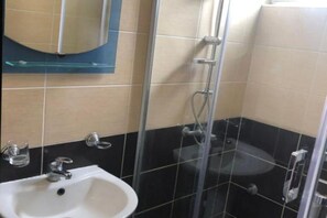 A bathroom with a glass-enclosed shower, a sink, and a mirror. - Casa Mila Apartments - Studio apartment with sea view (Ulcinj)