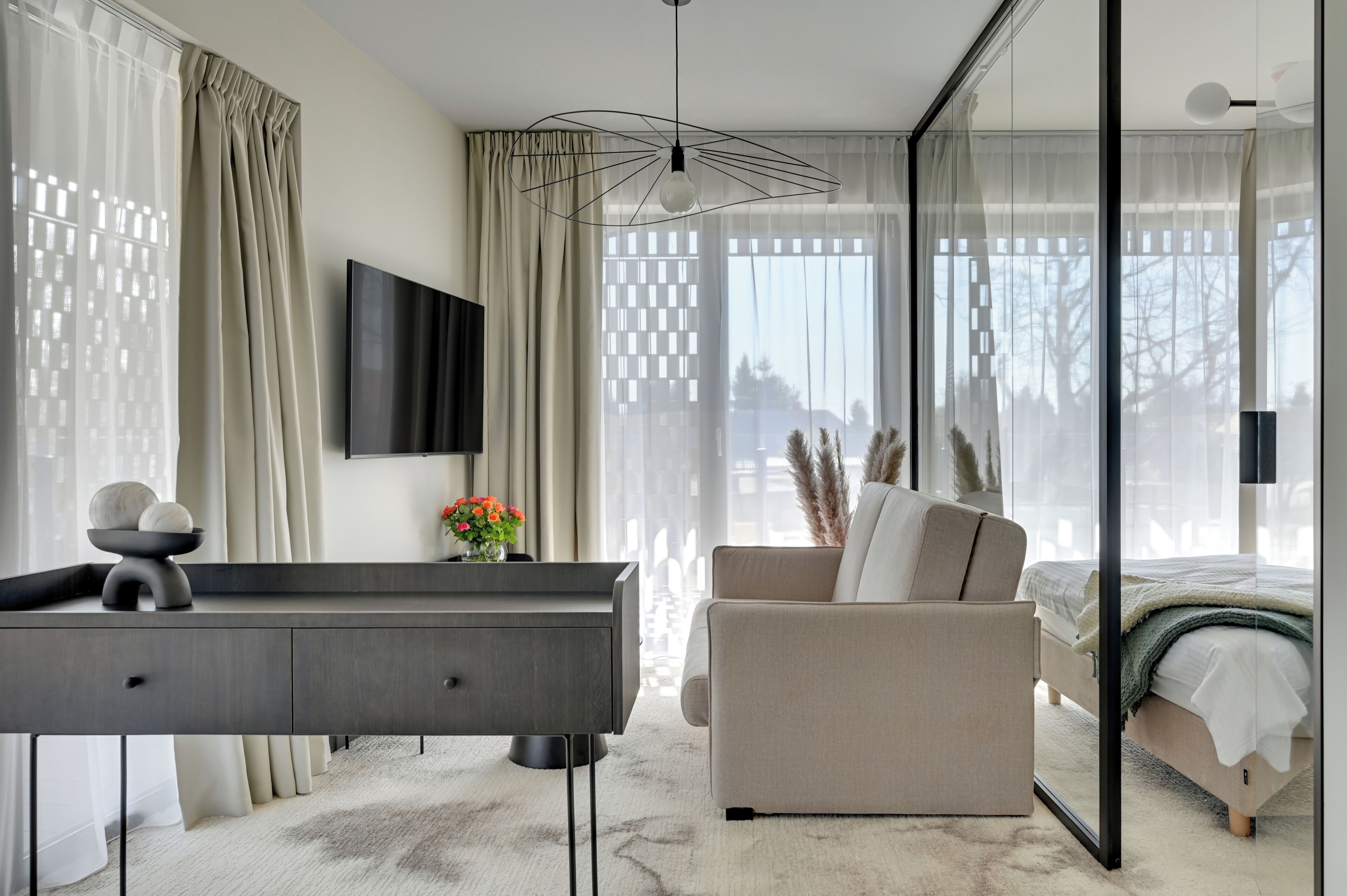 Une chambre à coucher moderne avec un lit, un canapé, un bureau et un téléviseur.