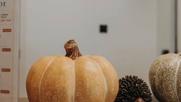 A table with decorative pumpkins and a pine cone, and a wall with the text 'GRANO APARTHOTEL'.