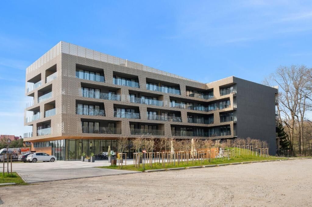 Ein mehrstöckiges Gebäude mit modernem architektonischen Design, das Balkone und große Fenster kombiniert.