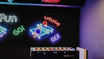 Ein Zimmer mit einem Tischtennis-Tisch, Neonleuchten und einer Deckenlampe.