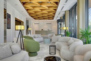 A modern interior with a geometric ceiling, plush seating, and large windows. - Grano Aparthotel Ustronie Morskie (Ustronie Morskie)