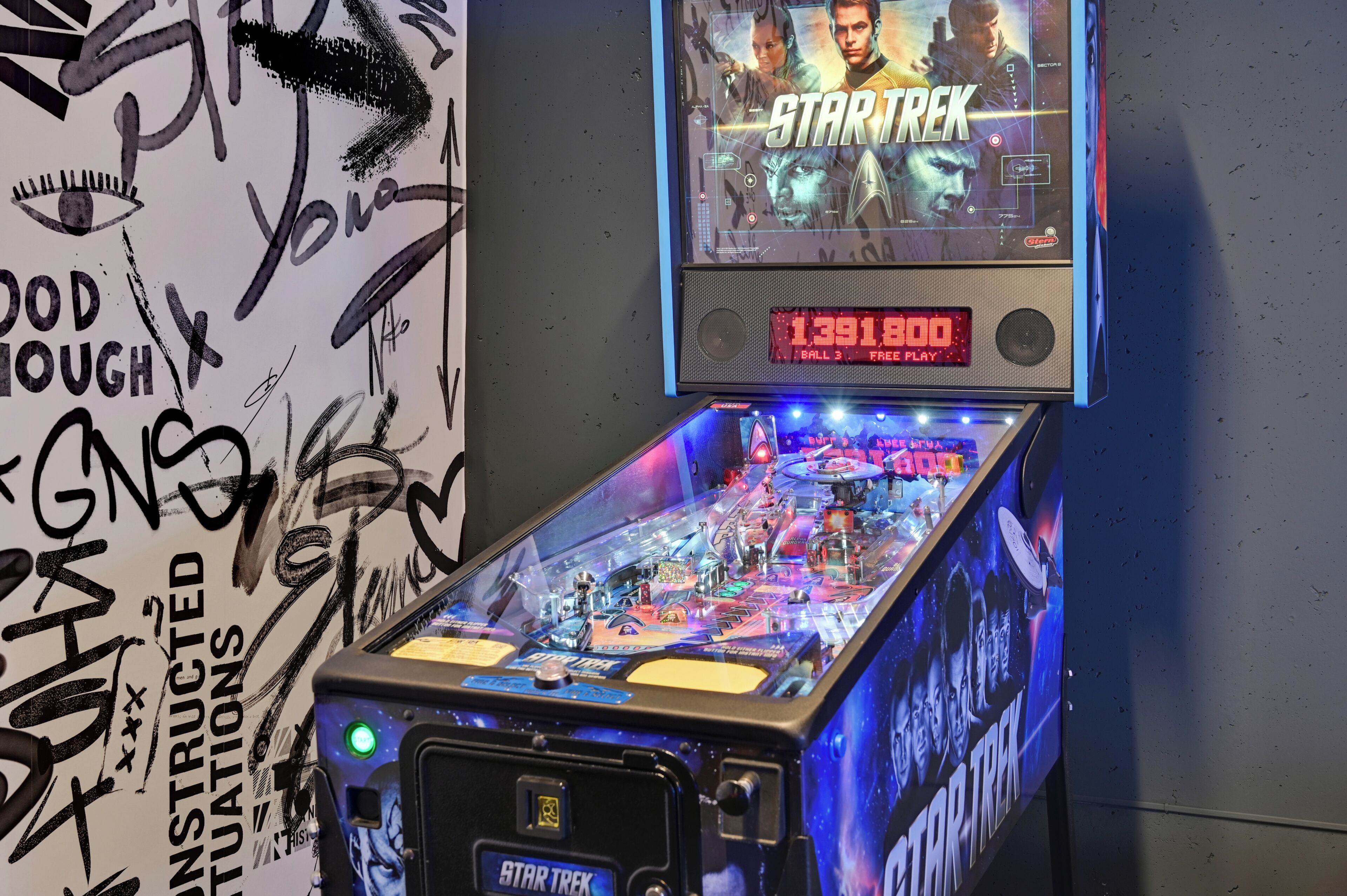 A pinball machine with a Star Trek theme, including a digital display and a play button.