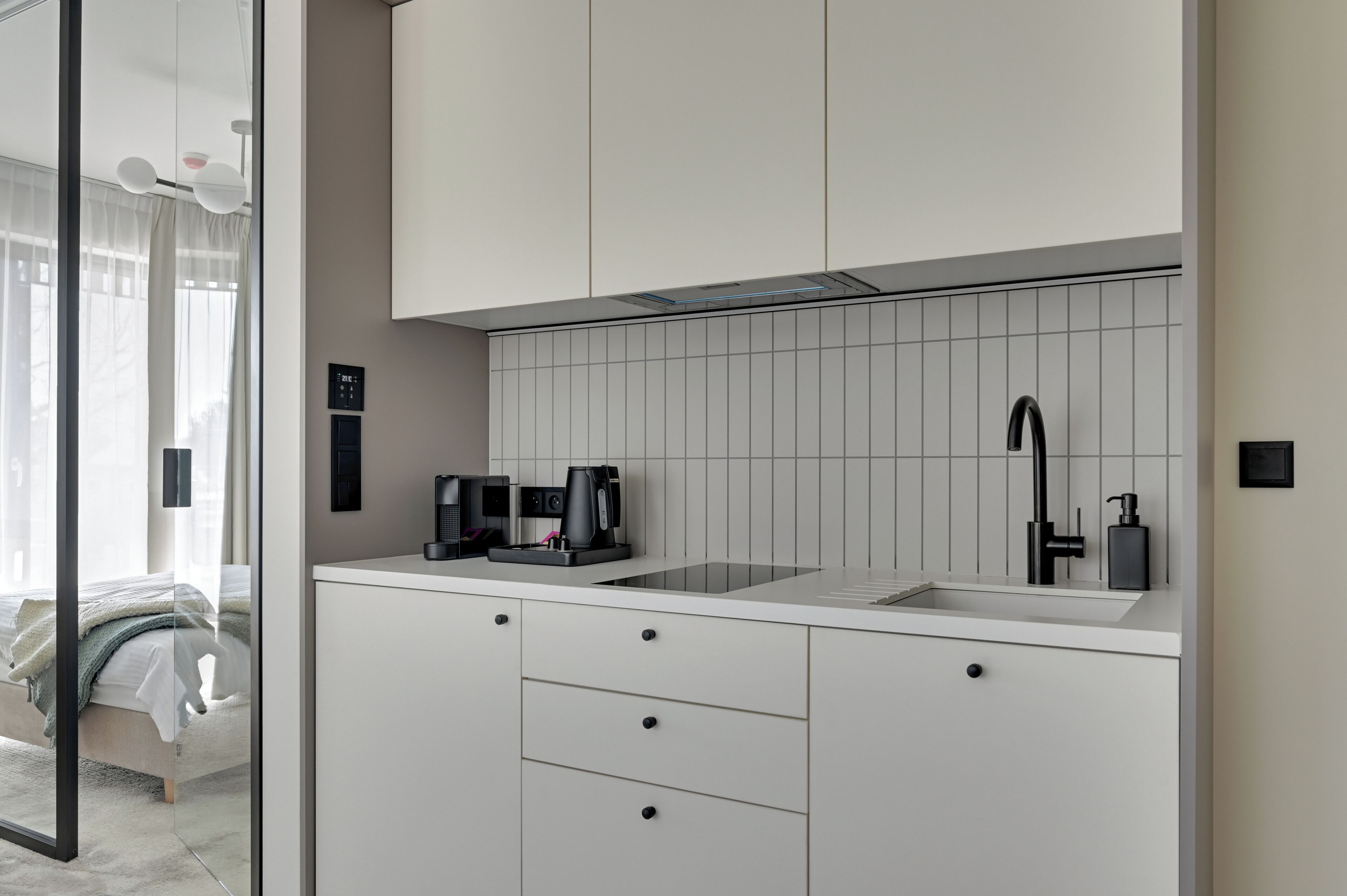 Eine moderne Küche mit weißen Schränken, einem schwarzen Wasserhahn und einer Kaffeemaschine.