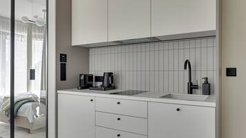 Eine moderne Küche mit weißen Schränken, einem schwarzen Wasserhahn und einer Kaffeemaschine.