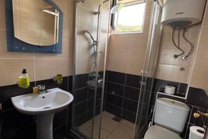 A bathroom with a glass-enclosed shower, a sink, a toilet, and a mirror. - Casa Mila Apartments - Studio apartment with sea view (Ulcinj)