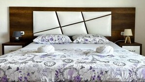 A bed with a patterned bedspread, two pillows, and a headboard with a geometric design. - Casa Mila Apartments - Studio apartment with sea view (Ulcinj)