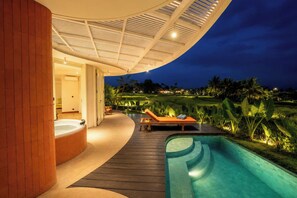 A modern outdoor pool area with a hot tub, lounge chairs, and a view of a landscaped garden at dusk. - Villa Merah Merah Ubud by Fays Hospitality (Kabupaten Gianyar)