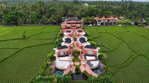 A multi-story hotel with a central courtyard, surrounded by lush green rice fields. - Villa Merah Merah Ubud by Fays Hospitality (Kabupaten Gianyar)