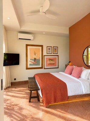 A bedroom with a bed, a bench, a TV, and framed pictures on the wall. - Villa Merah Merah Ubud by Fays Hospitality (Kabupaten Gianyar)