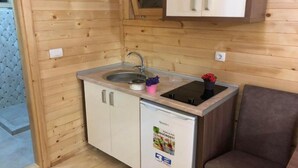 Een compacte keuken met een spoelbak, een kleine koelkast en een kast boven de spoelbak.