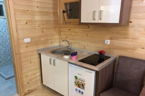 Eine kleine Küche mit Spüle, einem Kühlschrank und einem Schrank darüber.