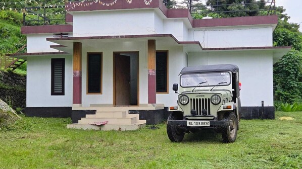 A white building with a front porch and a parked jeep in front.
