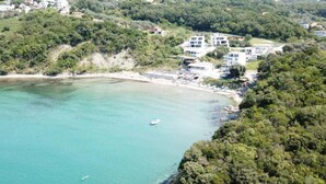 Une zone côtière avec des bâtiments à proximité d’une plage, un bateau sur l’eau et une végétation luxuriante.