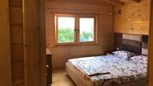 Une pièce en bois avec un lit, une fenêtre et une porte.