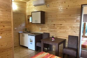 Ein kompakter Raum mit einer Küchenzeile, einem Esstisch mit zwei Stühlen und einem Bett.