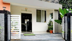 A modern entrance with a white gate, a small window, and potted plants. - Collection O Atlas DLF Formerly Hillside (Hyderabad)