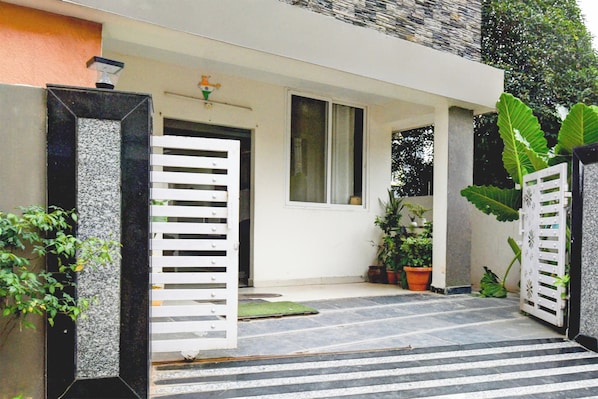 A modern house entrance with a white door, a small window, and potted plants. - Collection O Atlas DLF Formerly Hillside (Hyderabad)