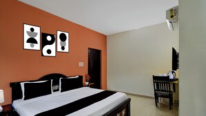 A hotel room with a bed, a desk, and a chair. There are three framed pictures on the wall. - Collection O Atlas DLF Formerly Hillside (Hyderabad)