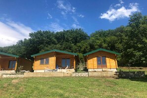 Three wooden cabins with green roofs, set against a backdrop of dense trees. - Casa Mila Bungalows - One bedroom bungalow (Ulcinj)