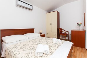 Ein Hotelzimmer mit Bett, Kleiderschrank, Schreibtisch mit Stuhl und Nachttisch mit Lampe.