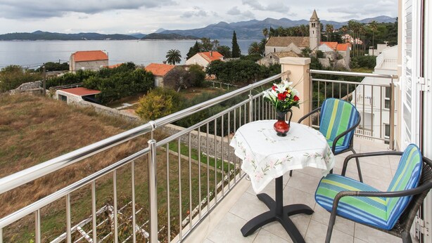 A balcony with a table, chairs, and a vase of flowers. - Apartments Ana Lopud - One-bedroom Apartment With Balcony and Sea View - 4 (Dubrovnik)