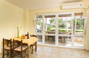 A dining area with a table set for four, chairs, a vase with flowers, and a bottle of wine. - Apartment With Terrace for 3 People (Dubrovnik)