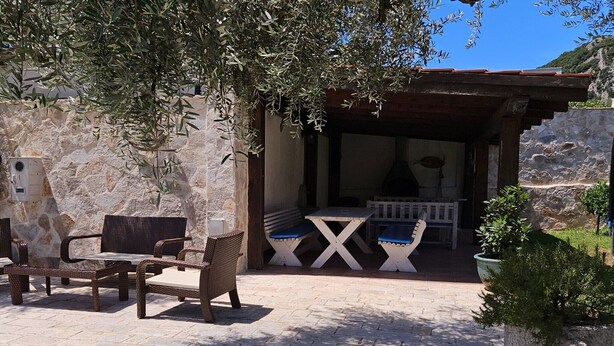 An outdoor seating area with wicker furniture and a stone wall. - Villa Ponto - Studio Apartment With Terrace (B3) (Kaluderac)