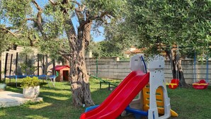 A playground with a red slide, a climbing structure, and a log cabin in the background. - Villa Ponto - Studio Apartment With Terrace (B3) (Kaluderac)