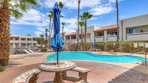 A swimming pool with a tiled deck, lounge chairs, and palm trees. - Work, Hike & Swim: Central Tucson Condo w/ Pool (Tucson)