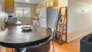 A kitchen with a dining table, chairs, a refrigerator, cabinets, a window, and a ladder. - Work, Hike & Swim: Central Tucson Condo w/ Pool (Tucson)