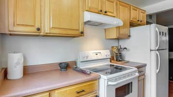 A kitchen with wooden cabinets, a white stove, and a refrigerator.