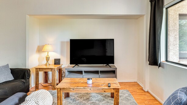 A living room with a sofa, a coffee table, a TV, and a lamp. - Work, Hike & Swim: Central Tucson Condo w/ Pool (Tucson)