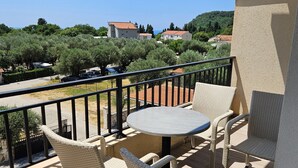Ein Balkon mit Korbmöbeln und einem Tisch, mit Blick auf einen Parkplatz und Grünflächen.
