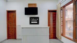 Zona de recepción con televisor de pantalla plana montado sobre un mostrador, puertas de madera y un amplio ventanal con vistas al exterior.