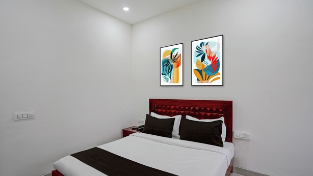 Habitación de hotel con una cama, una mesita de noche, un teléfono y dos cuadros en la pared.