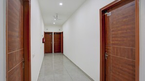 Un pasillo con dos puertas de madera, un ventilador de techo y un extintor.