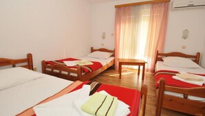 A hotel room with three wooden beds, a small table, and a window with sheer curtains. - Glory Sanctuary Retreat - Triple Room with Balcony (Medugorje)