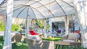 A covered outdoor seating area with wicker furniture and a hanging chair. - Glory Sanctuary Retreat - Triple Room with Balcony (Medugorje)