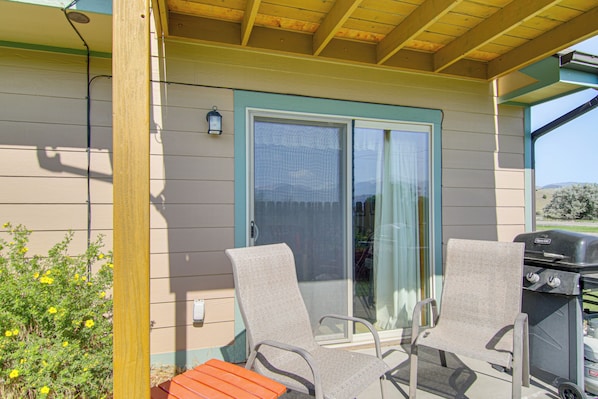 An outdoor patio area with two chairs, a barbecue grill, and a sliding glass door. - Yellowstone Basecamp! Emigrant Home w/ Mtn Views (Emigrant)